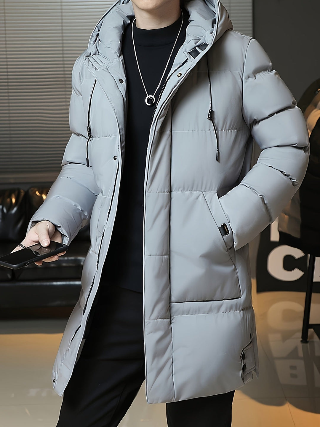 Man wearing Barnaby grey longline coat, holding phone