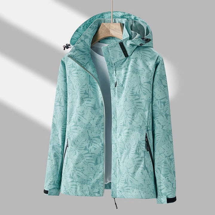 Freya hooded leaf print rain jacket in turquoise, front view on hanger