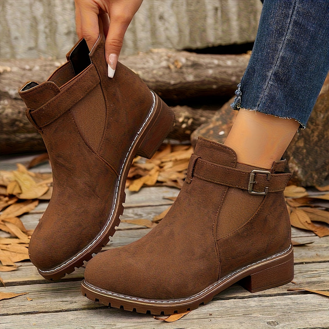 Marigold buckle strap Chelsea boots in brown, held by hand
