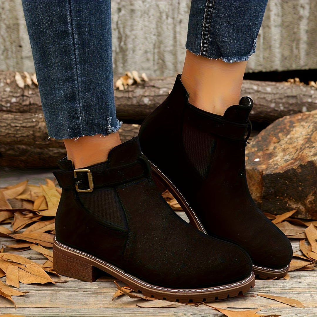 Marigold buckle strap Chelsea boots in black, side view on feet