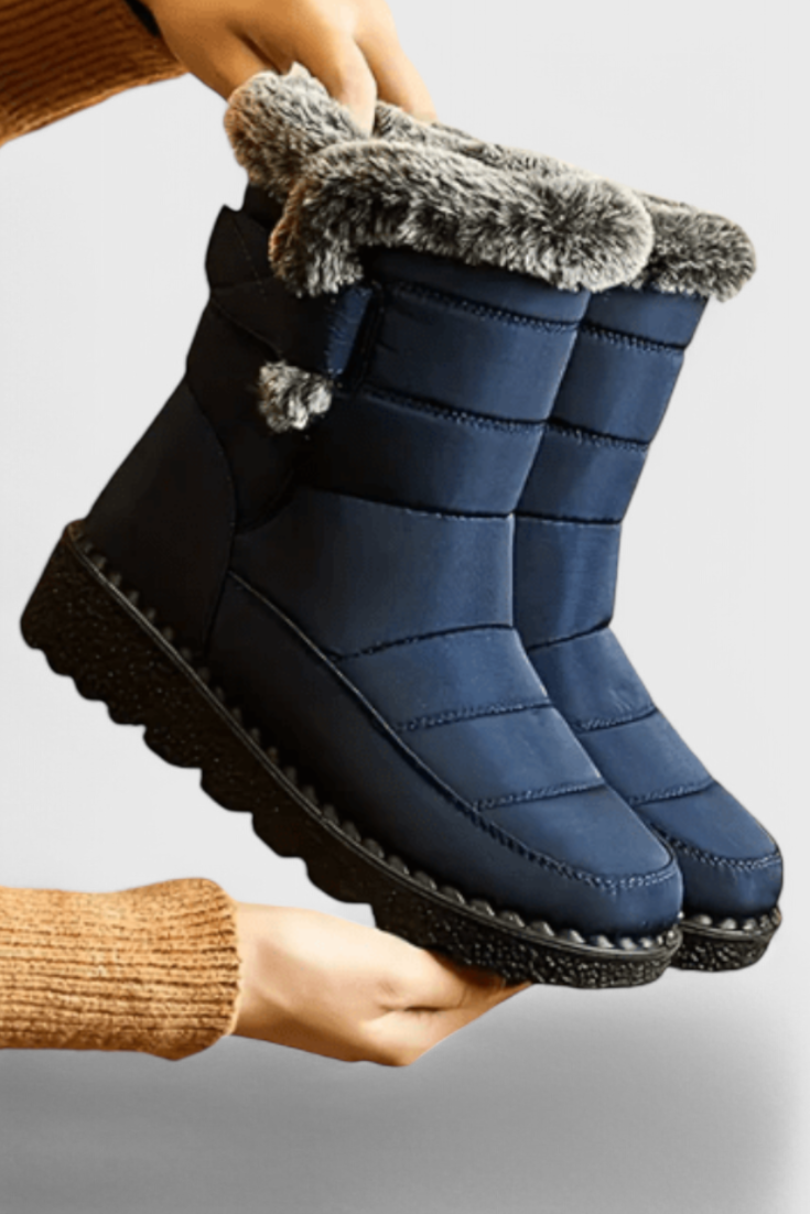 Marigold navy fur-trim waterproof snow boots held by hand, side view