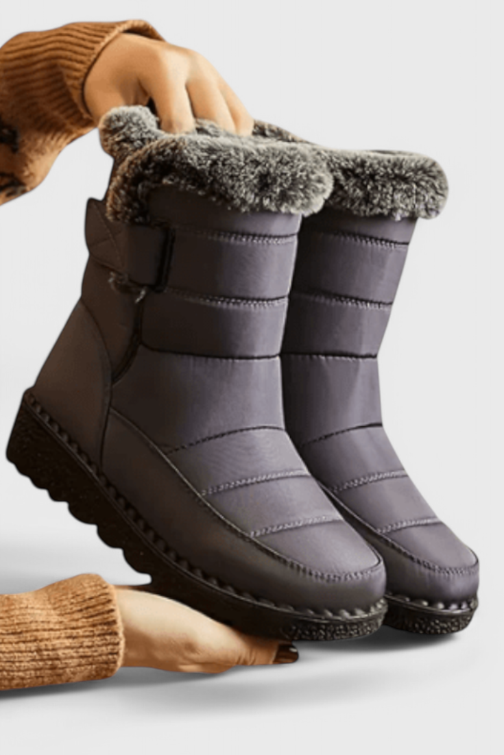 Marigold grey fur-trim waterproof snow boots held by hand, side view