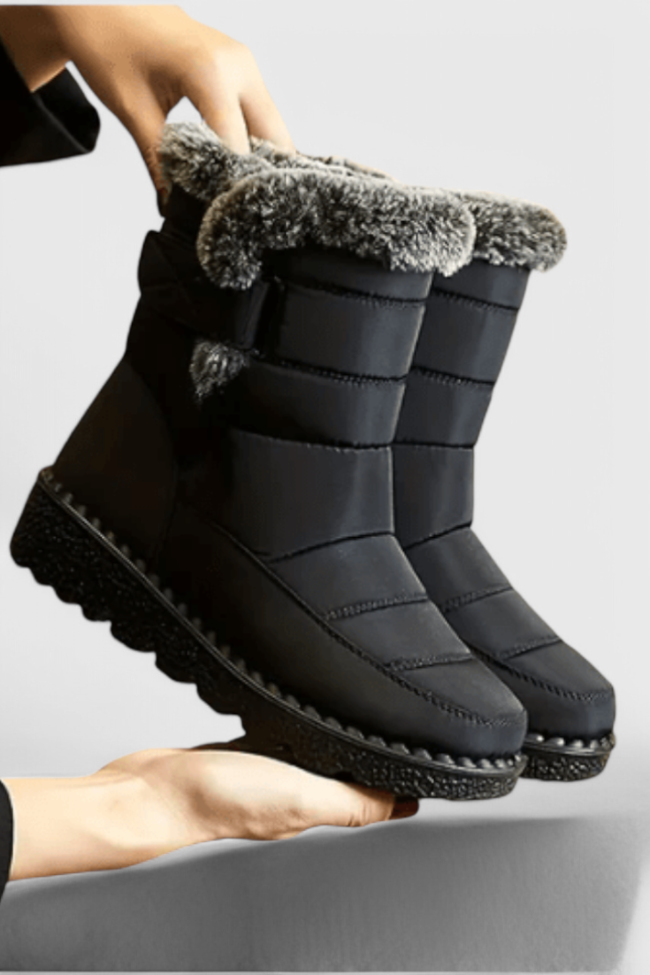 Marigold black fur-trim waterproof snow boots held by hand, side view