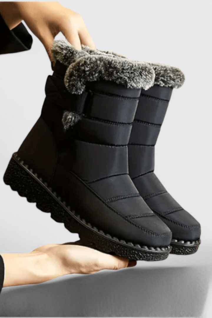 Marigold black fur-trim waterproof snow boots held by hand, side view