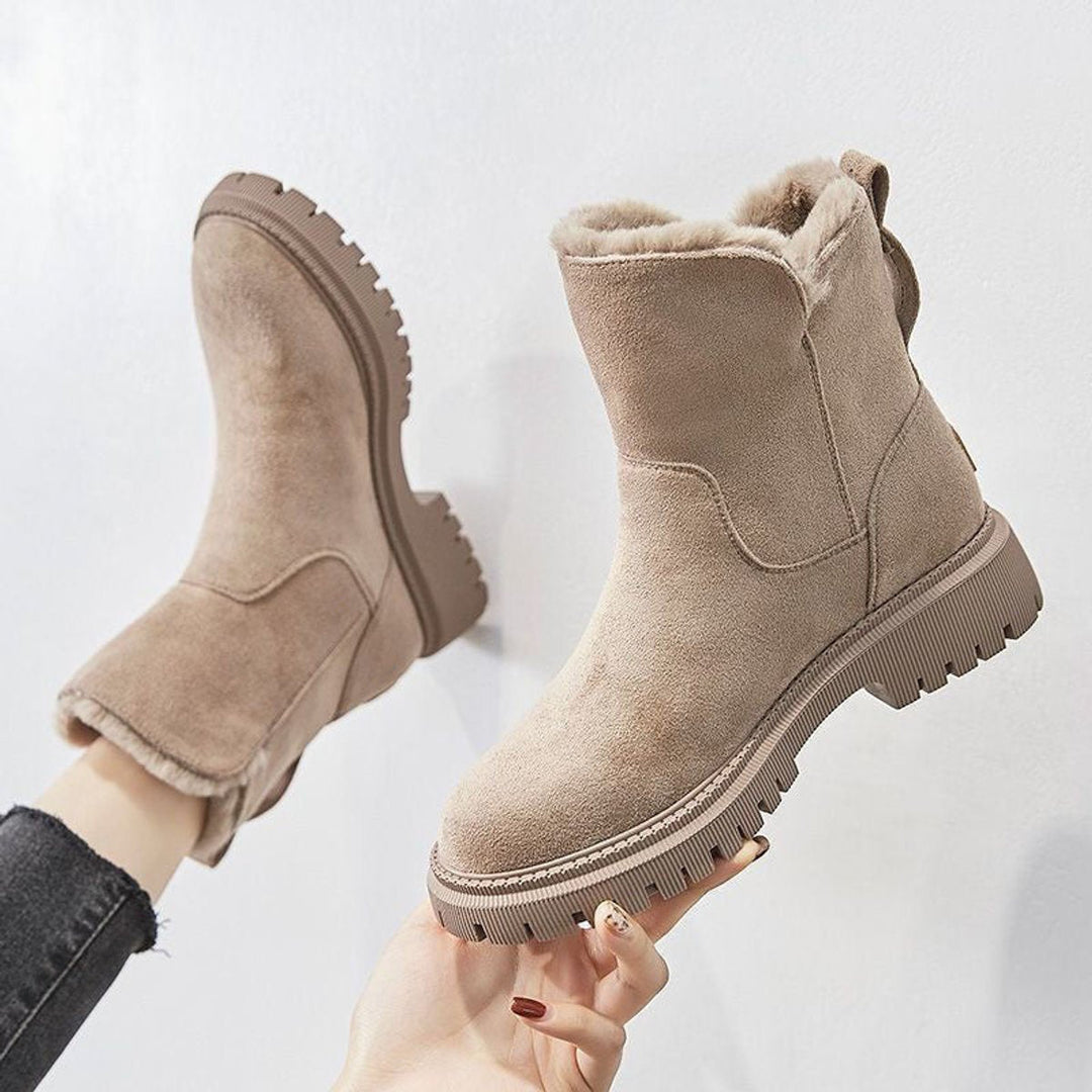 Primrose fur lined slip-on ankle boots held up by hand, side profile view