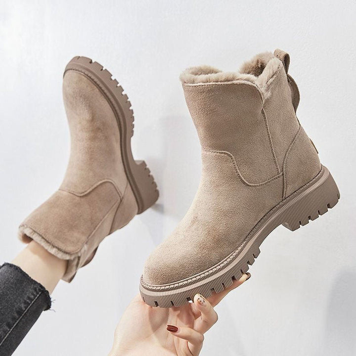 Primrose fur lined slip-on ankle boots held up by hand, side profile view