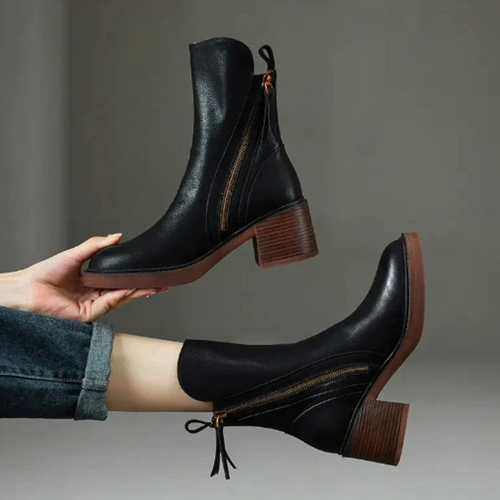Black Rosalind ankle boots held and worn, showing zip and heel