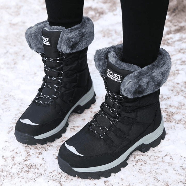 Verity black fur trim lace-up snow boots worn outdoors on snowy ground, close-up angle