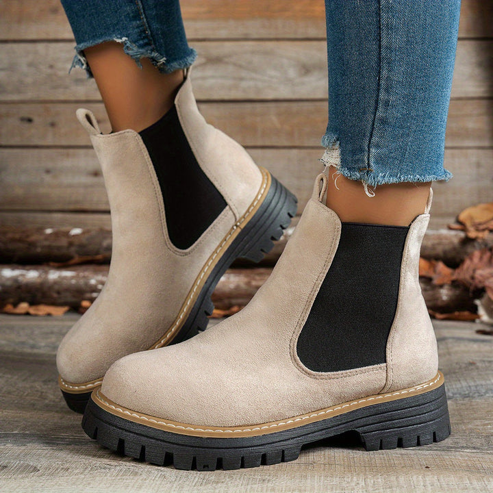 Beige Chelsea boots worn with ripped denim jeans, side view