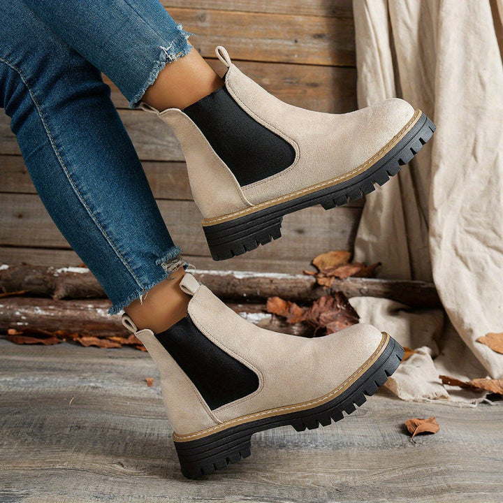 Beige Chelsea boots worn with ripped denim jeans, walking pose