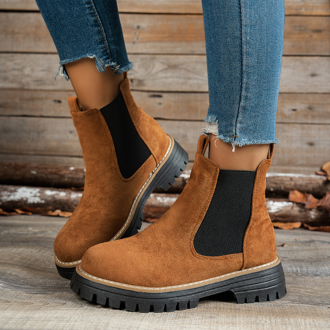 Brown Chelsea boots worn with ripped denim jeans, side view
