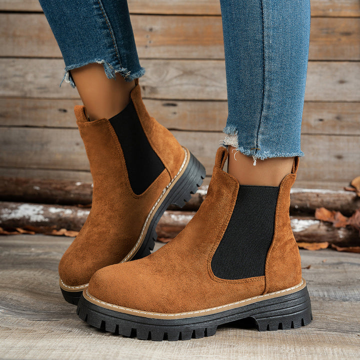 Brown Chelsea boots worn with ripped denim jeans, side view