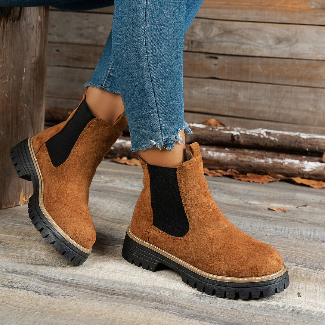 Brown Chelsea boots worn with ripped denim jeans, close-up side view
